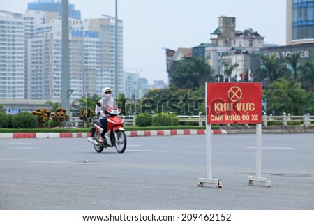 HANOI, VIETNAM - JUL 13, 2014: Unidentified Vietnamese woman riding motorbike via a sign of no parking and restricted area in Hanoi capital.