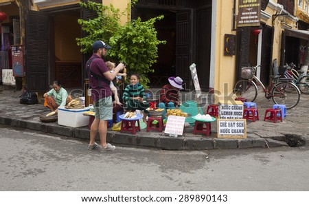 Hoi An, Vietnam - Jun 20, 2015: Vietnamese food vendor selling traditional cakes and noodles on a street side in Hoi An ancient town. Hoi An is recognized as a World Heritage Site by UNESCO.