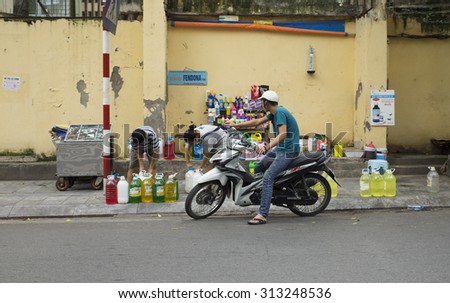 Hanoi, Vietnam - Sep 2, 2015: Vietnamese man on motorcycle buying cocking oil at a flea mobile stall on the side walk of a street in Hanoi capital.