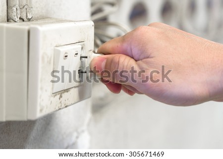 man hand plugging in appliance to old electrical outlet in wall