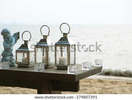 three candle light and cupid statue with the beach background