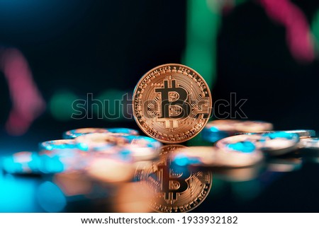 Bitcoin cryptocurrency with colorfull blurred candlestick chart in the background and reflection