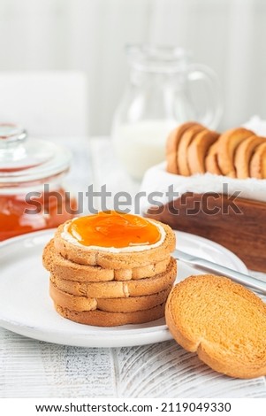 Continental italian Breakfast. Apricot Jam and Butter on Rusks or Fette Biscottate or Zwieback, toasted round Bread. Milk. White table. Vertical image. Сток-фото © 