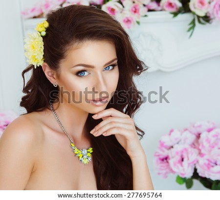 Portrait of Beautiful Young Woman with Flowers and Jewelry. Healthy Long Hair and Clear Skin. Close Up