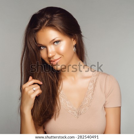 Portrait of Young Beautiful Brunette Woman with Jewelry Ring. Healthy Long Hair and Clean Skin on Grey Background