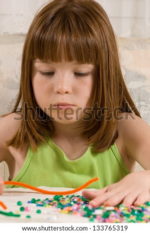 Young girl making a bead bracelet