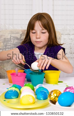Young girl in the process of coloring Easter Eggs - Step one, placing the egg on a spoon