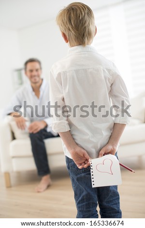 boy offering a drawing heart to his father