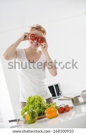 woman in the kitchen makes a joke with tomatoes on her eyes