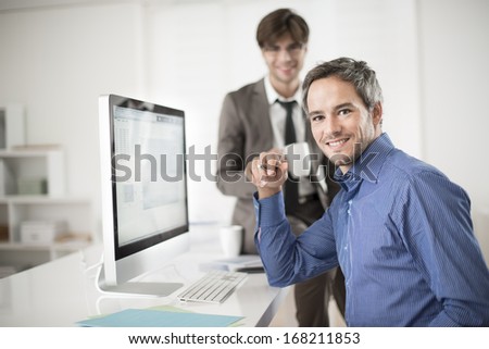 two colleagues speaks about business at office in front of computer