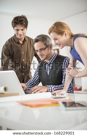 team discusses about a work project around a computer