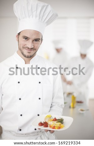 chef presenting a dish with his team in background