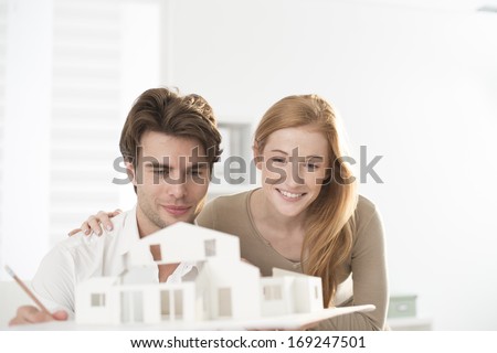 Couple studying a construction project with a model house