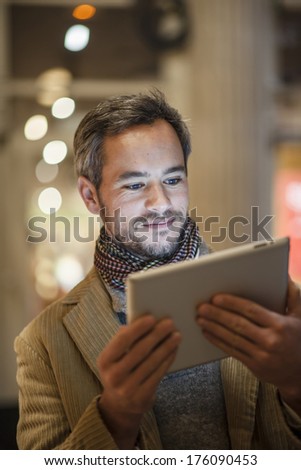 handsome man using a digital tablet outside with city lights at the background