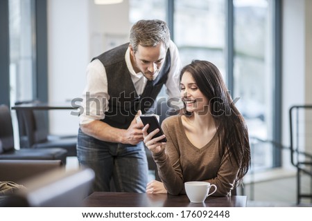 two young people watching a smartphone in a cafe