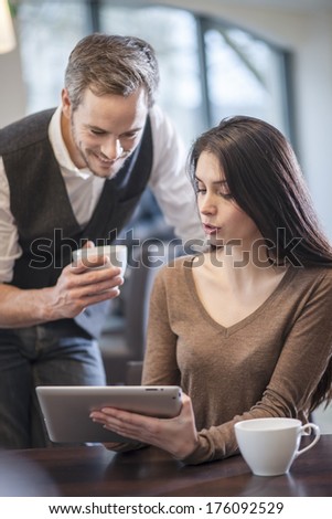 two young people watching a digital tablet in a cafe