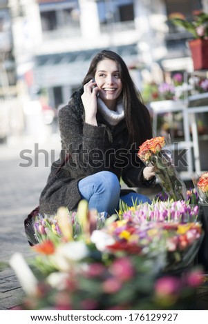 beautiful woman at phone choosing flowers at the florist shop