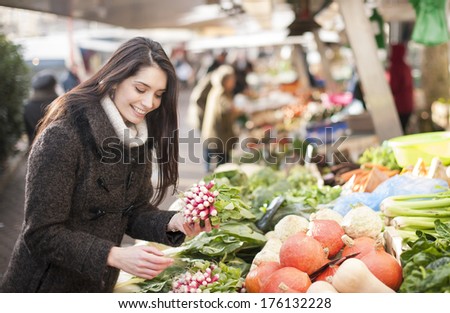 young woman choosing vegetables on a market