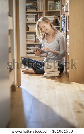 young student sit on the floor working on her digital tablet near family library