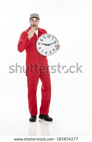 Full length portrait of unhappy worker in dungarees with a clock in arms