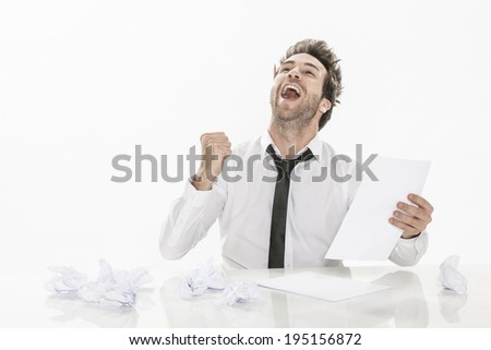 expressive young businessman sitting in front of a sheet of paper and a pencil and a few drafts on the table