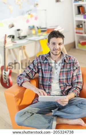 young man sitting on the couch and surfing on a digital tablet