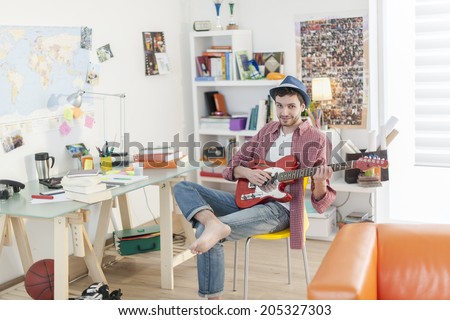 young student is playing guitar in his apartment