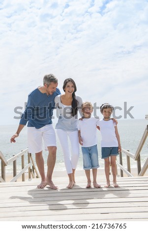happy family  standing on a wood pontoon in front of the sea in summertime