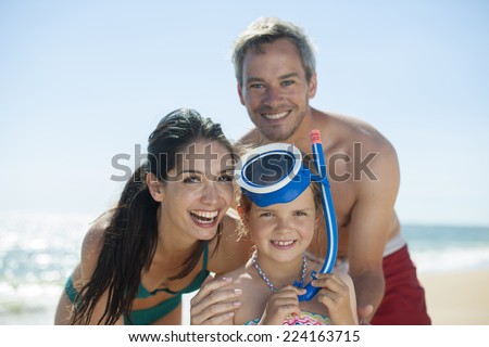 portrait of a family in swimsuit at the beach with the little girl with a diving mask