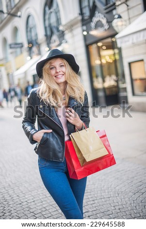 beautiful trendy young woman with hat and leather jacket doing shopping in the city, shopping bags in her arm