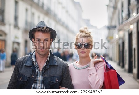portrait of a  trendy young couple walks in the city, the young woman has shopping bags at her arm
