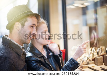 At Christmastime in the city a young trendy couple looking at watches in a showcase