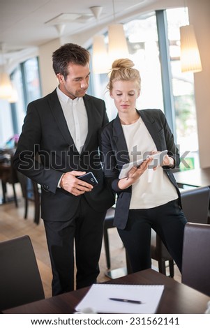 Couple of colleague  wearing suits,  using a digital tablet in a meeting