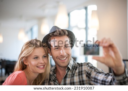trendy Couple taking a Selfie with a phone, in a coffeeshop