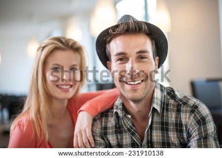 portrait of a trendy couple in a cafe, man wears a hat