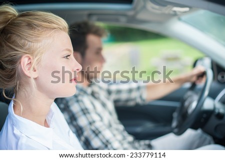 handsome couple sitting in a car, woman\'s face at foreground and man driving