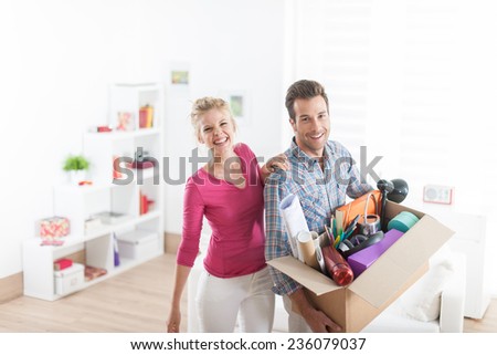 portrait of an handsome couple moving in  a new apartment and carrying a box with various objects