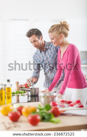 Handsome couple cooking on a cooktop at home, vegetables on the work plan