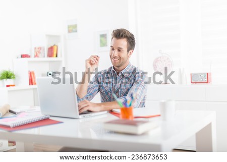 Handsome young man using a laptop in a modern office