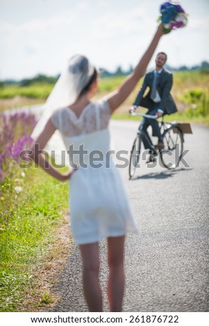 The groom is coming back for his bride on a bike. Beautiful couple having fun for their honeymoon