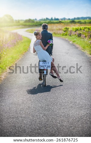 A newlywed couple is taking the road on a bike. They are having fun for their honeymoon