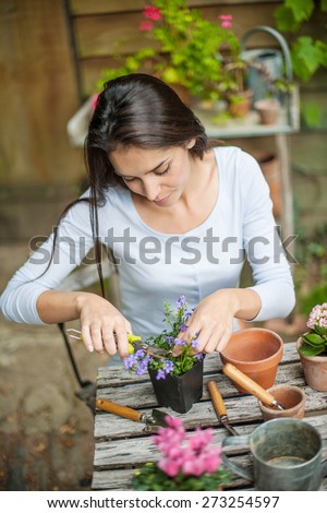Beautiful girl looking after her flowers at the garden table