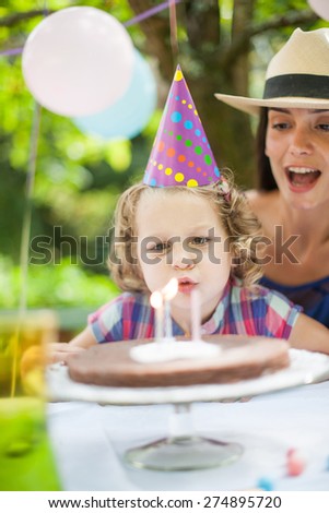 garden party for little girl\'s birthday with mum, Girl blows her candles