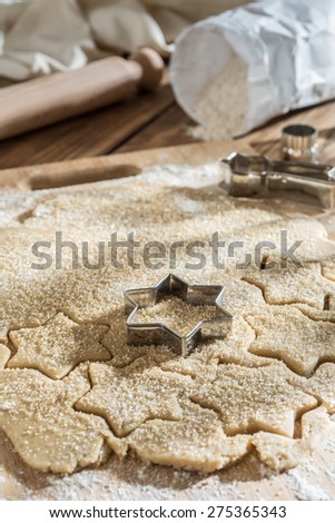 Closeup on cookie cutter on cake dough and rolling pin on a wooden board
