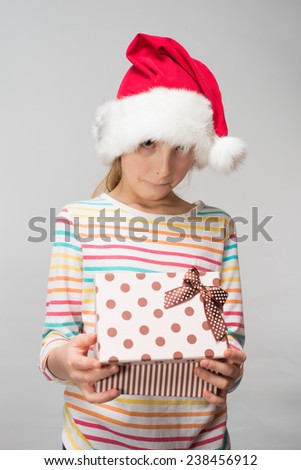 Portrait of happy little girl in santa hat with gift box