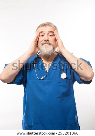 Feeling tired and stressed. Depressed mature surgeon touching his head with hands and keeping eyes closed while standing