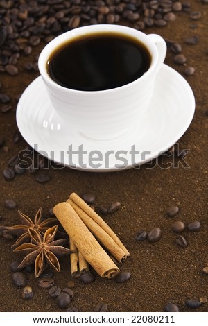 Cup with coffee against a background from milled and grain powder coffee,to the fore cinnamon and badian.