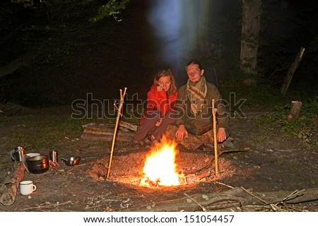 Young people warm themselves by the fire at night.