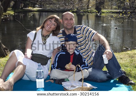 Happy parents and son having picnic in park