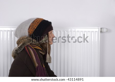 Young girl is standing by a white heater